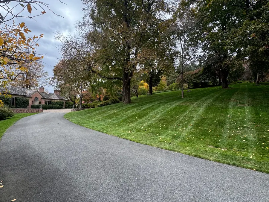 The same hillside lawn after cleanup, leaves gone, grass freshly cut with clean mower stripes.
